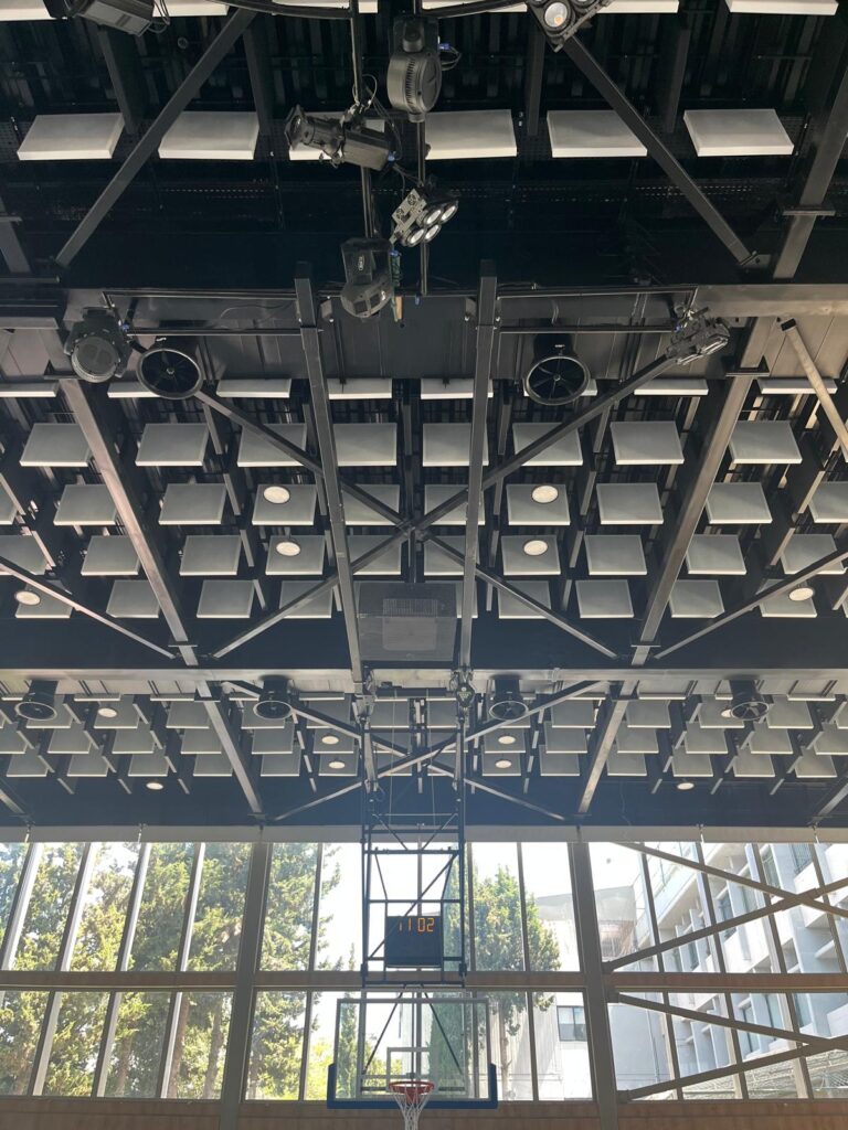 Wide view of acoustic baffles installed across the ceiling of the International College basketball court.