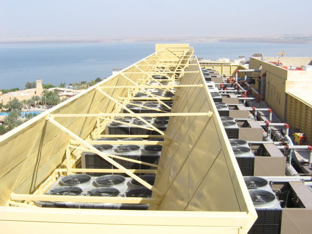Acoustic panels surrounding rooftop chiller systems for noise mitigation.